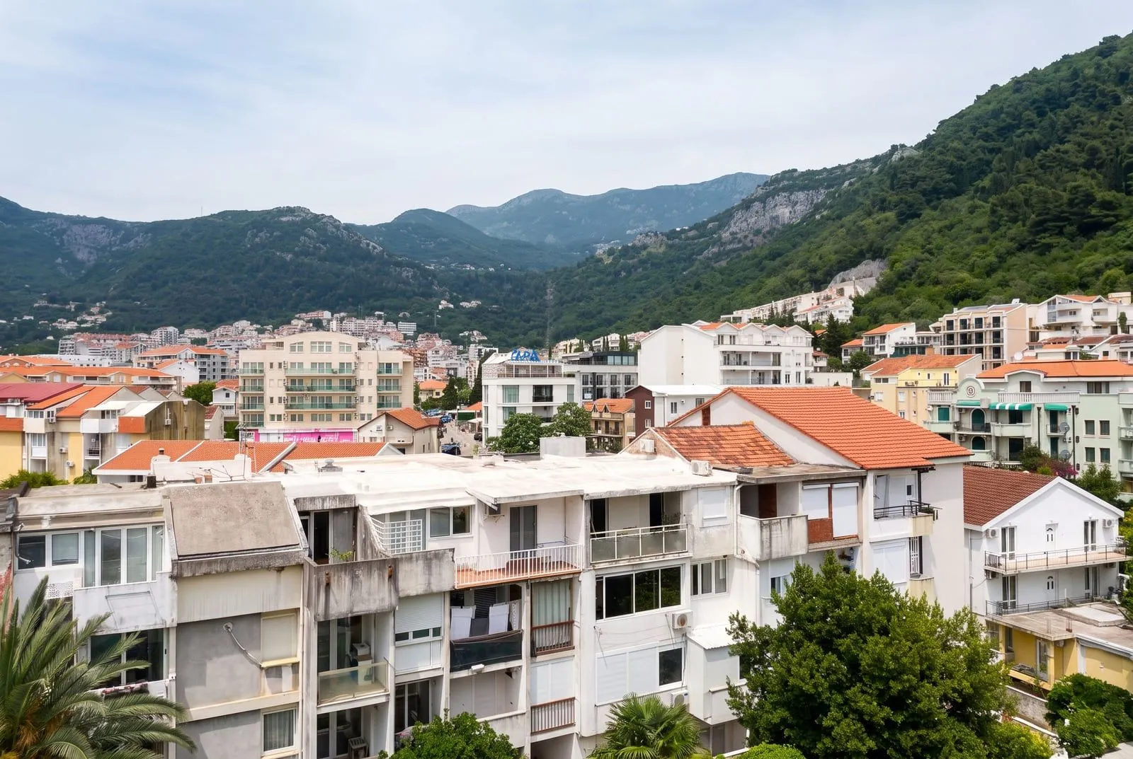 Pogled sa terase na gradske zgrade i planine.