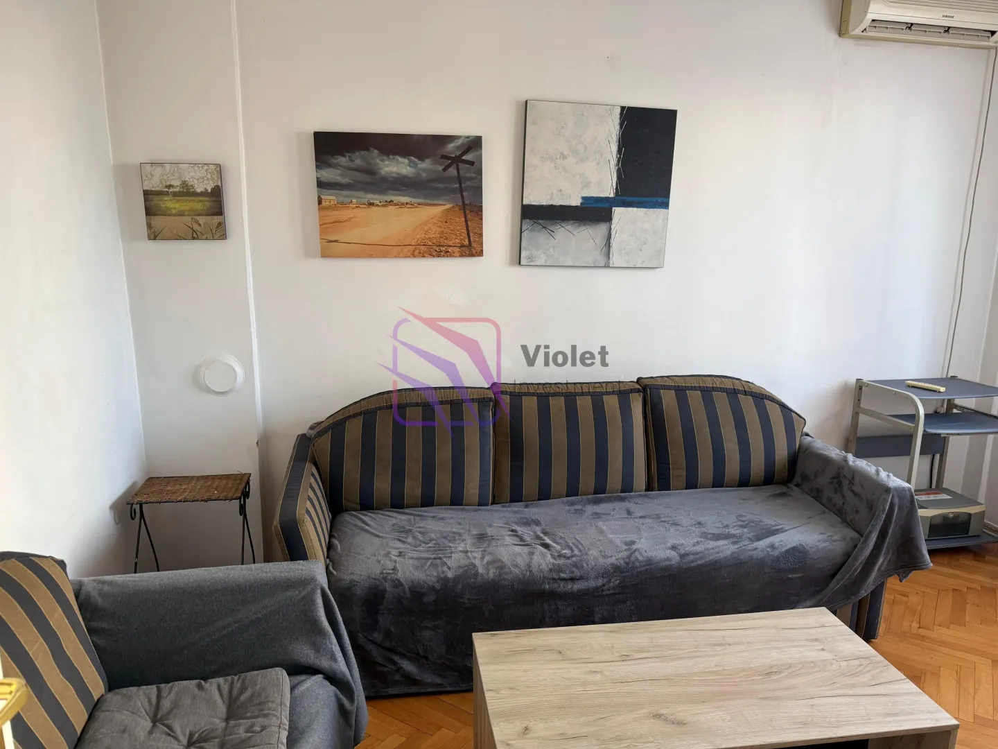 Living room with a sofa, coffee table, and paintings on the wall.