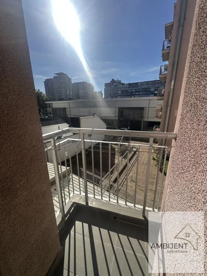 Manji balkon sa metalnom ogradom i pogledom na gradsko okruženje.