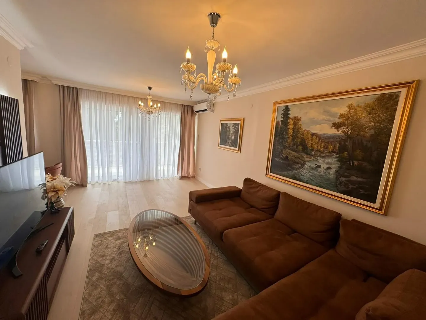 Living room with a sectional sofa, television, and a large artwork on the wall.