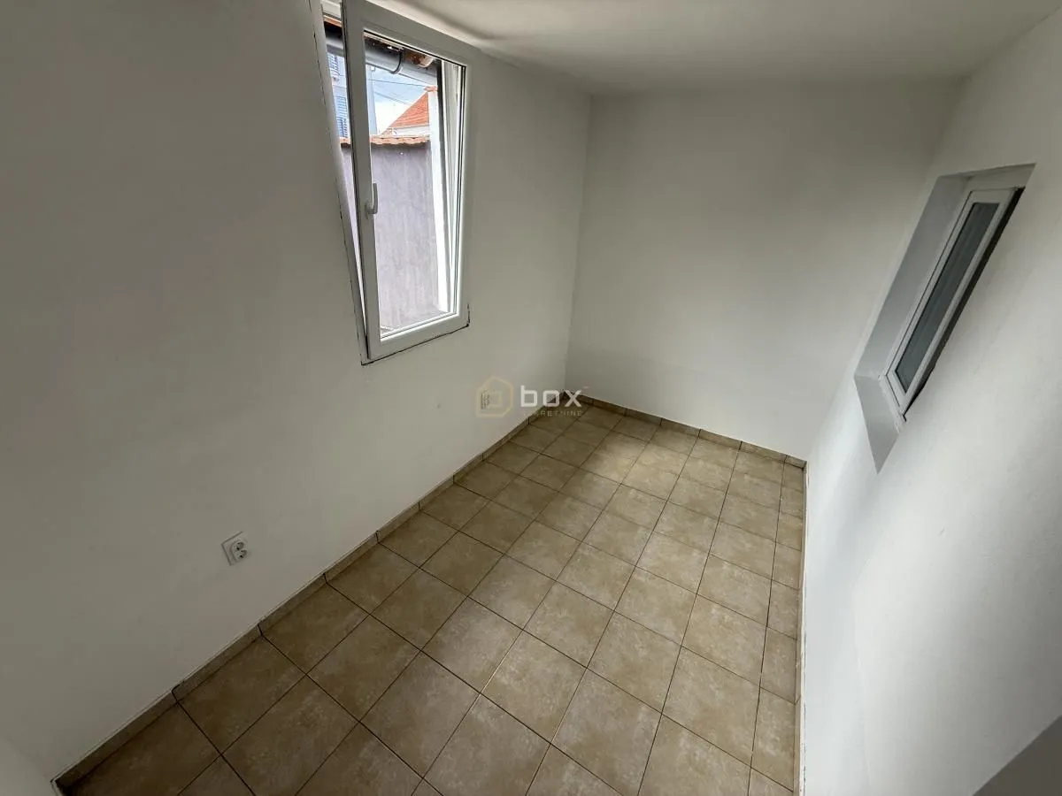Empty room with ceramic tiled floor and two windows.