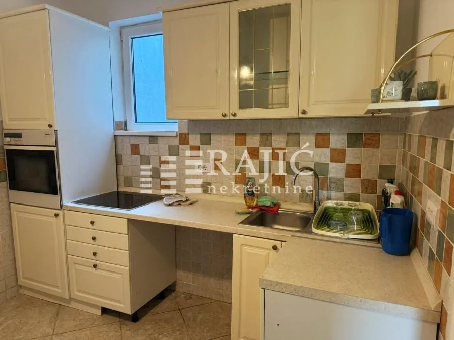 Small kitchen with light-colored cabinets and tiled walls.
