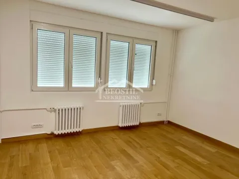 Prazna soba sa parketom i belim prozorima sa roletnama. - image 2