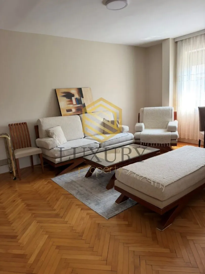 Living room with sofa, armchair, and parquet flooring.
