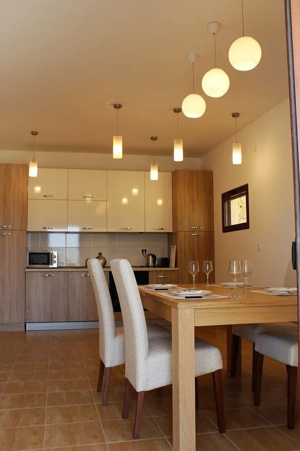 Dining area with a wooden table and kitchen in the background.