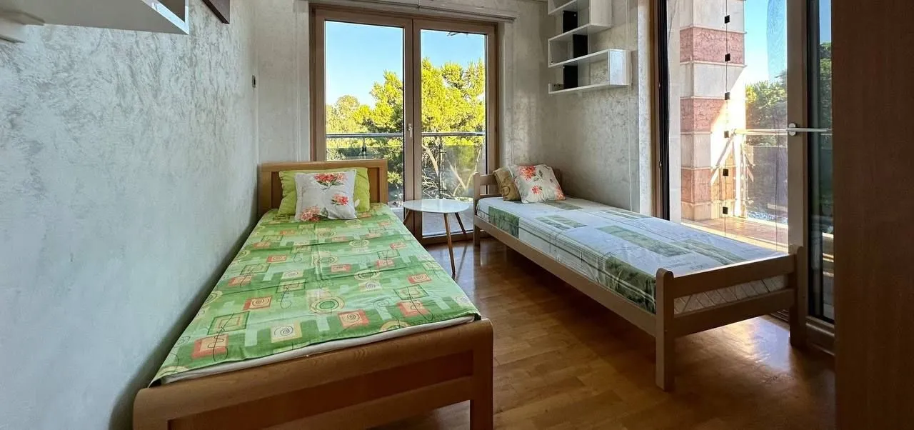 Spavaća soba sa dva singl kreveta i izlazom na terasu.