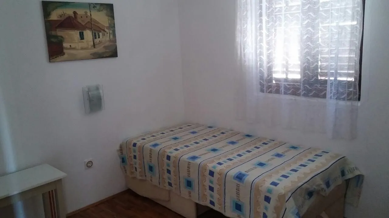 Mala spavaća soba sa jednim krevetom pored prozora.