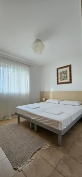 Svijetla spavaća soba sa bračnim krevetom, bijelom posteljinom i prozorom sa zavjesama. - image 9