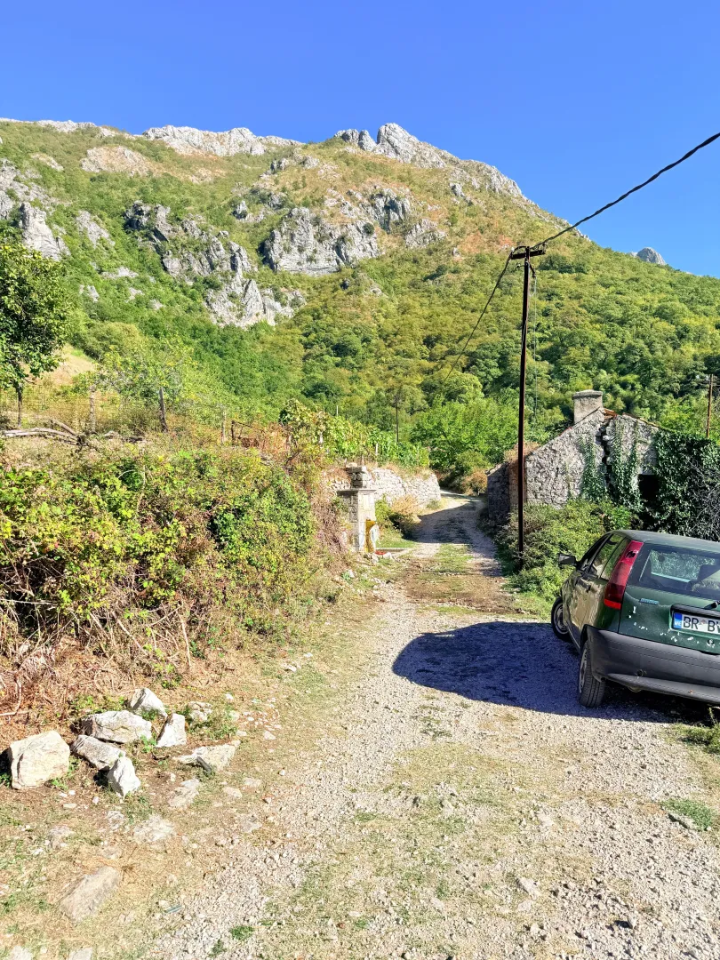 Seoski put ispred kamene kuće sa pogledom na planinu.