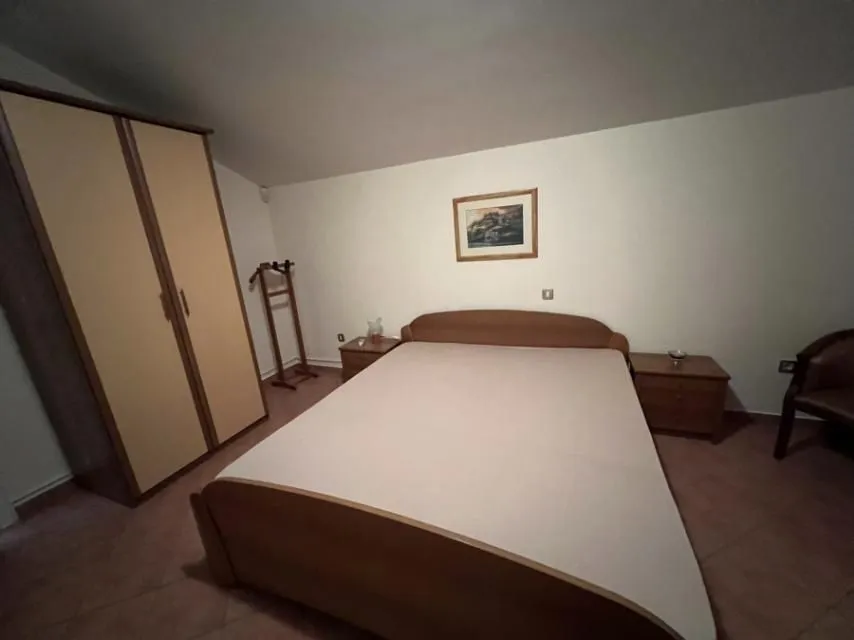 Simply furnished bedroom with a double bed and a wardrobe.
