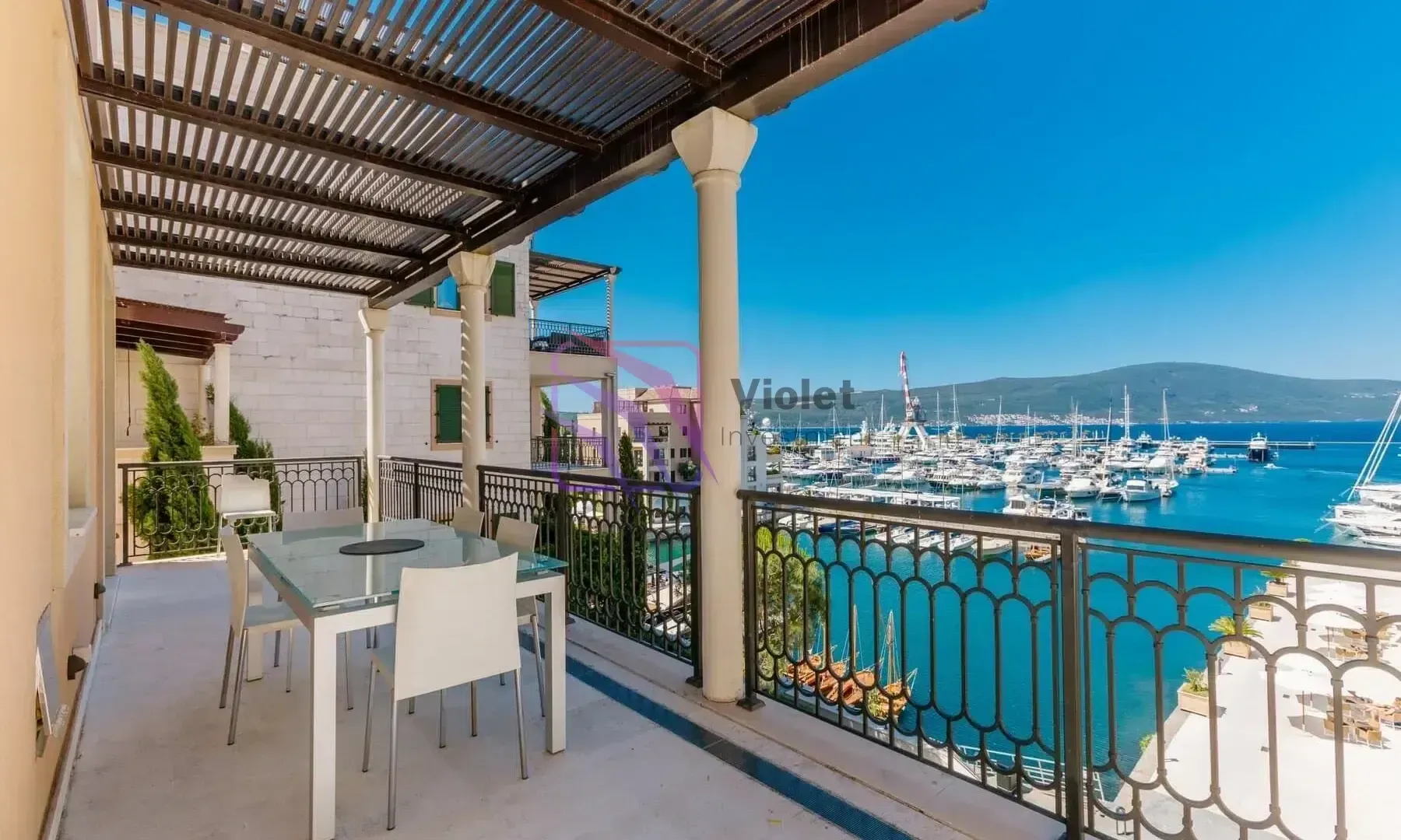 Spacious covered terrace with a dining table and a view of the marina.