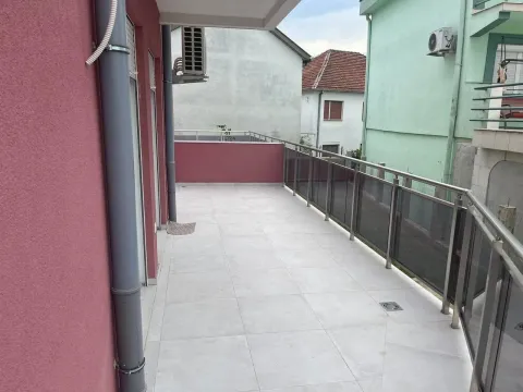 Prostrana popločana terasa sa metalnom ogradom i pogledom na susjedne objekte. - image 6