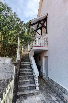 Spoljašnji prilaz sa stepeništem i balkonom kuće okružene zelenilom. - image 11