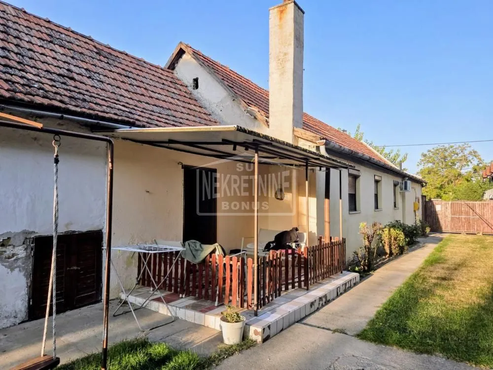 Pogled na spoljašnjost kuće sa natkrivenom terasom i dvorištem.