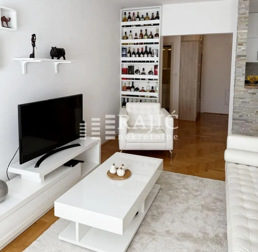Living room with furniture, TV, and white elements.