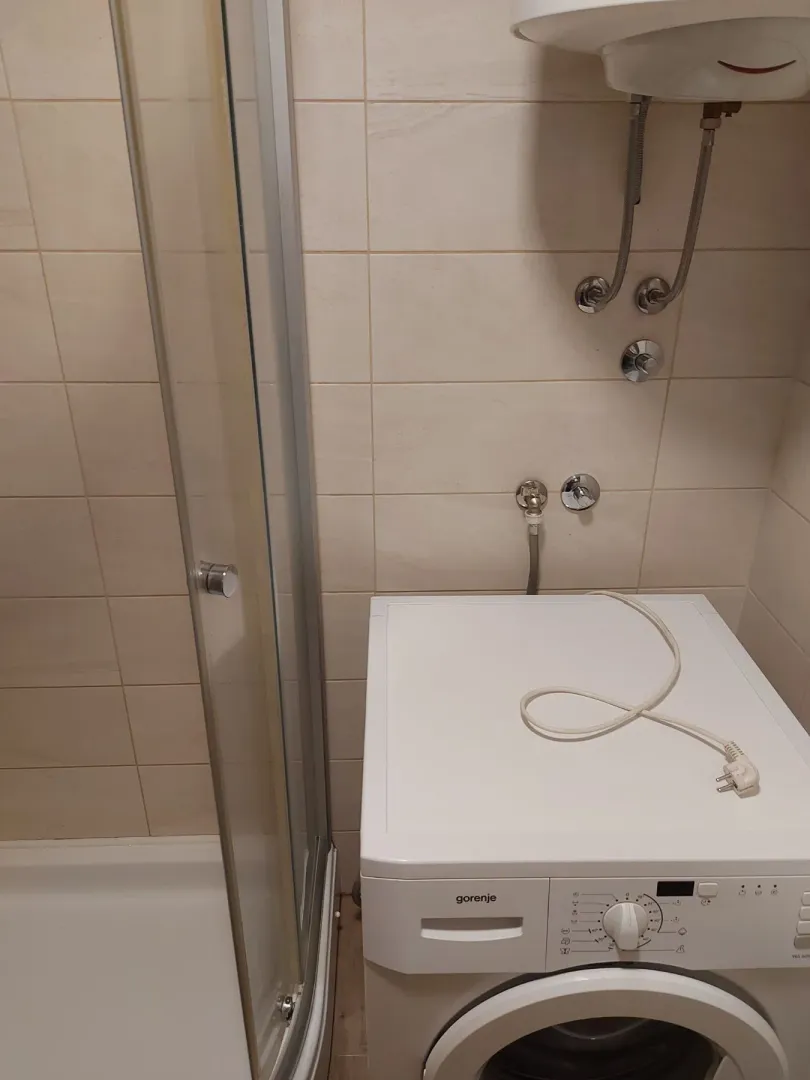 Dio kupatila sa veš mašinom i tuš kabinom.