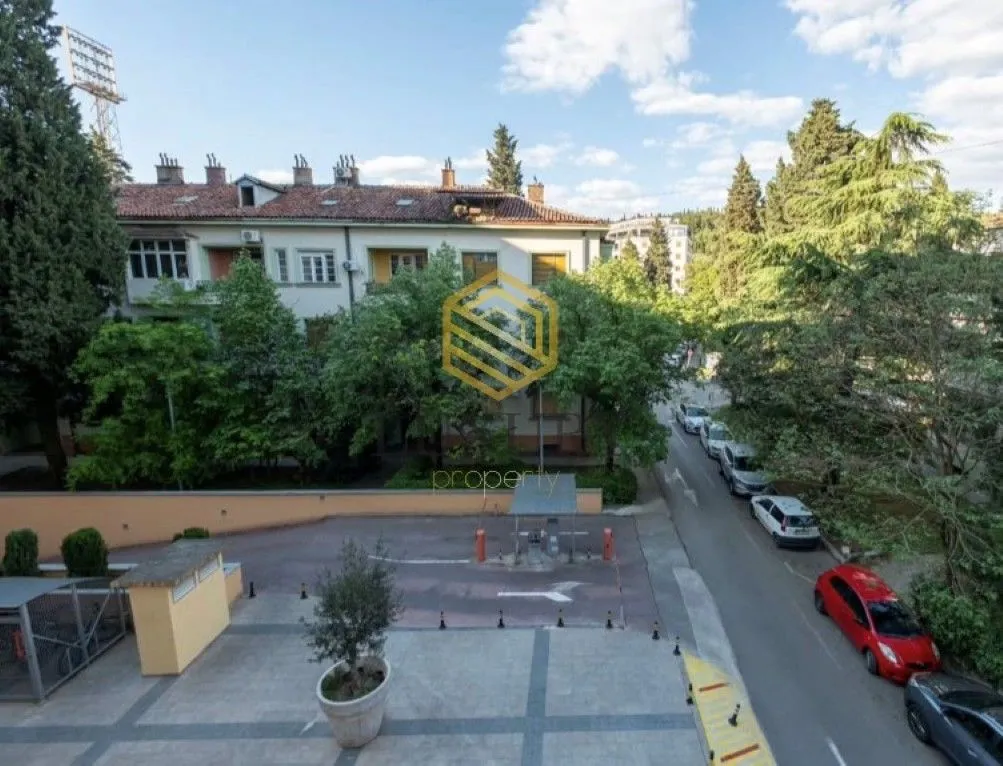 Pogled sa terase na dvorište i okolne zgrade sa zelenilom.