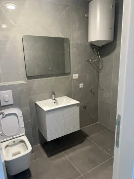Modern equipped bathroom with toilet, sink, and water heater. - image 5