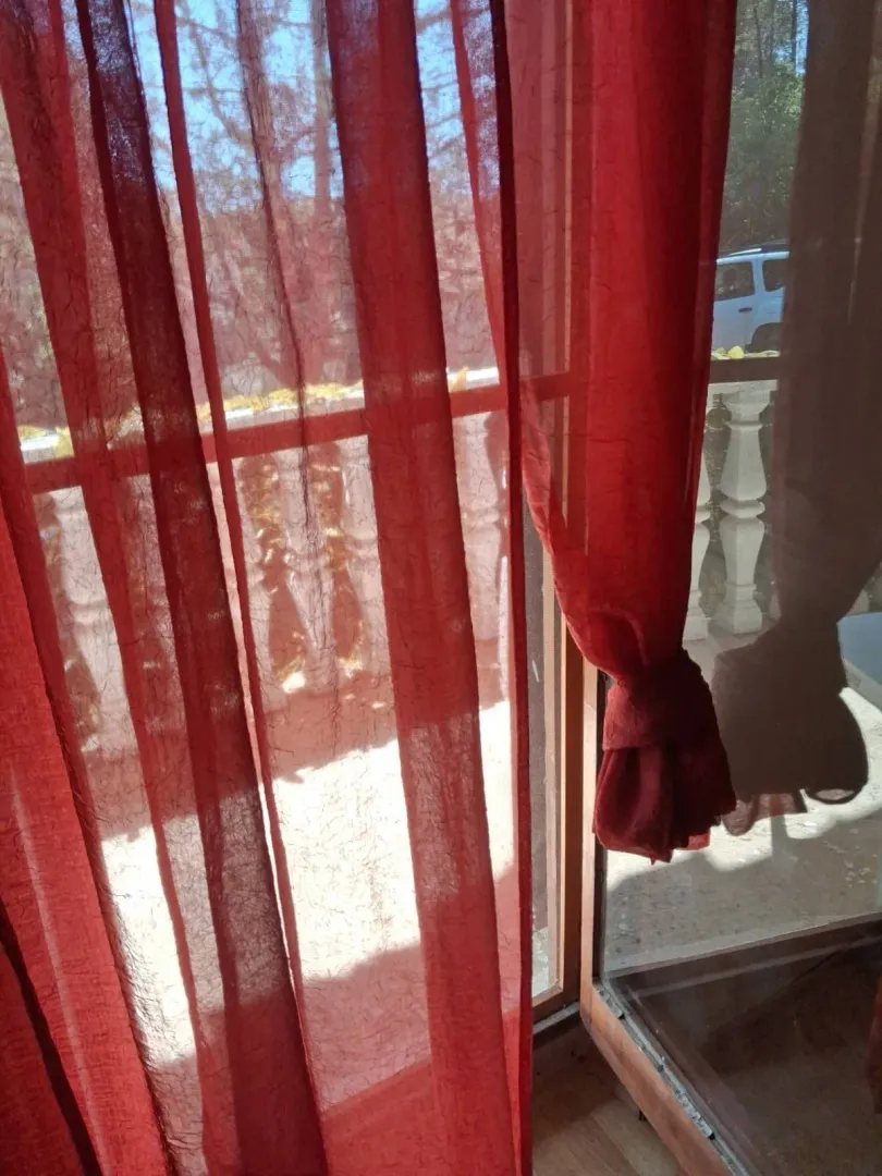 A view through red curtains onto a balcony with balustrades.