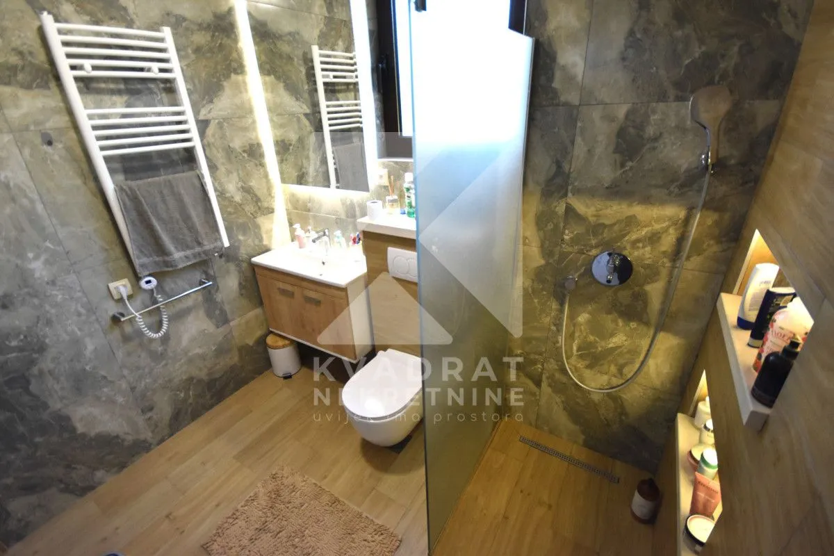 A modern bathroom equipped with a walk-in shower, washbasin, and toilet.