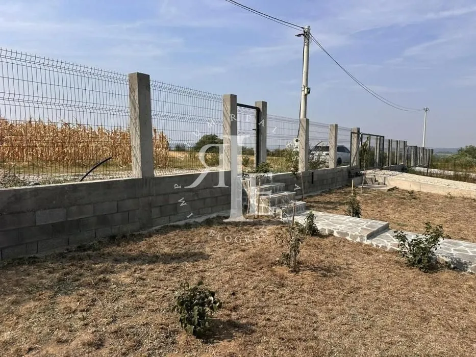 Fenced yard with a gate and paved pathways.