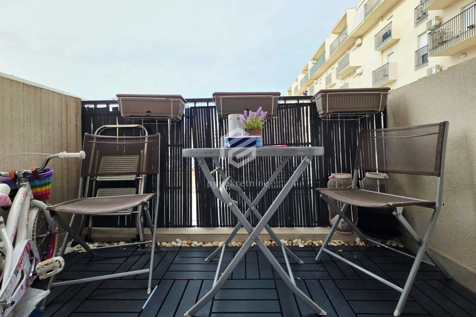 Manji namješten balkon sa stolom i stolicama.