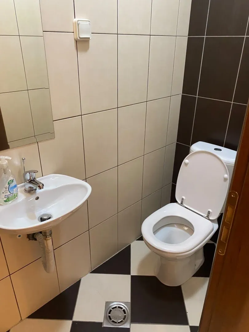 Manje kupatilo sa umivaonikom, ogledalom i toalet šoljom.