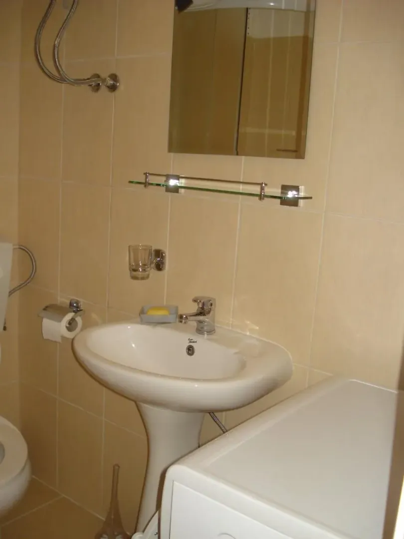 Small bathroom with a sink, mirror, and beige tiles.