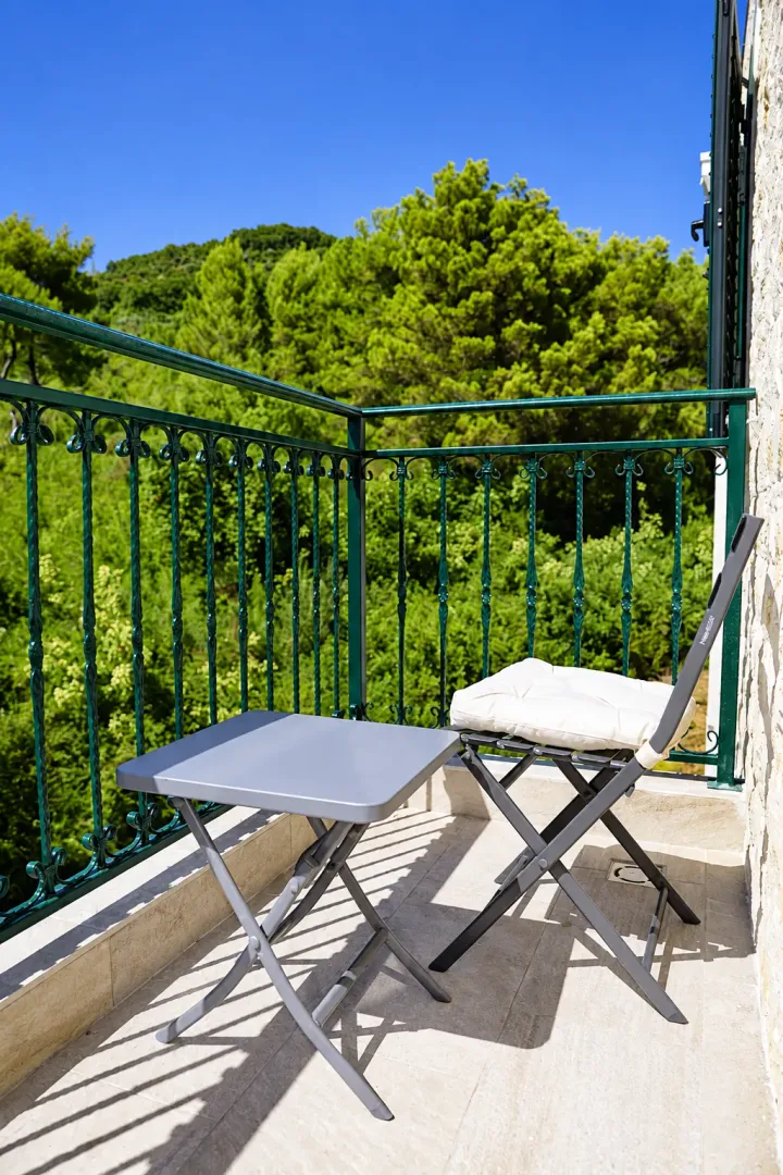 Manji namješteni balkon sa stolom i stolicom i pogledom na zelenilo.