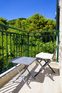 Manji namješteni balkon sa stolom i stolicom i pogledom na zelenilo. - image 13