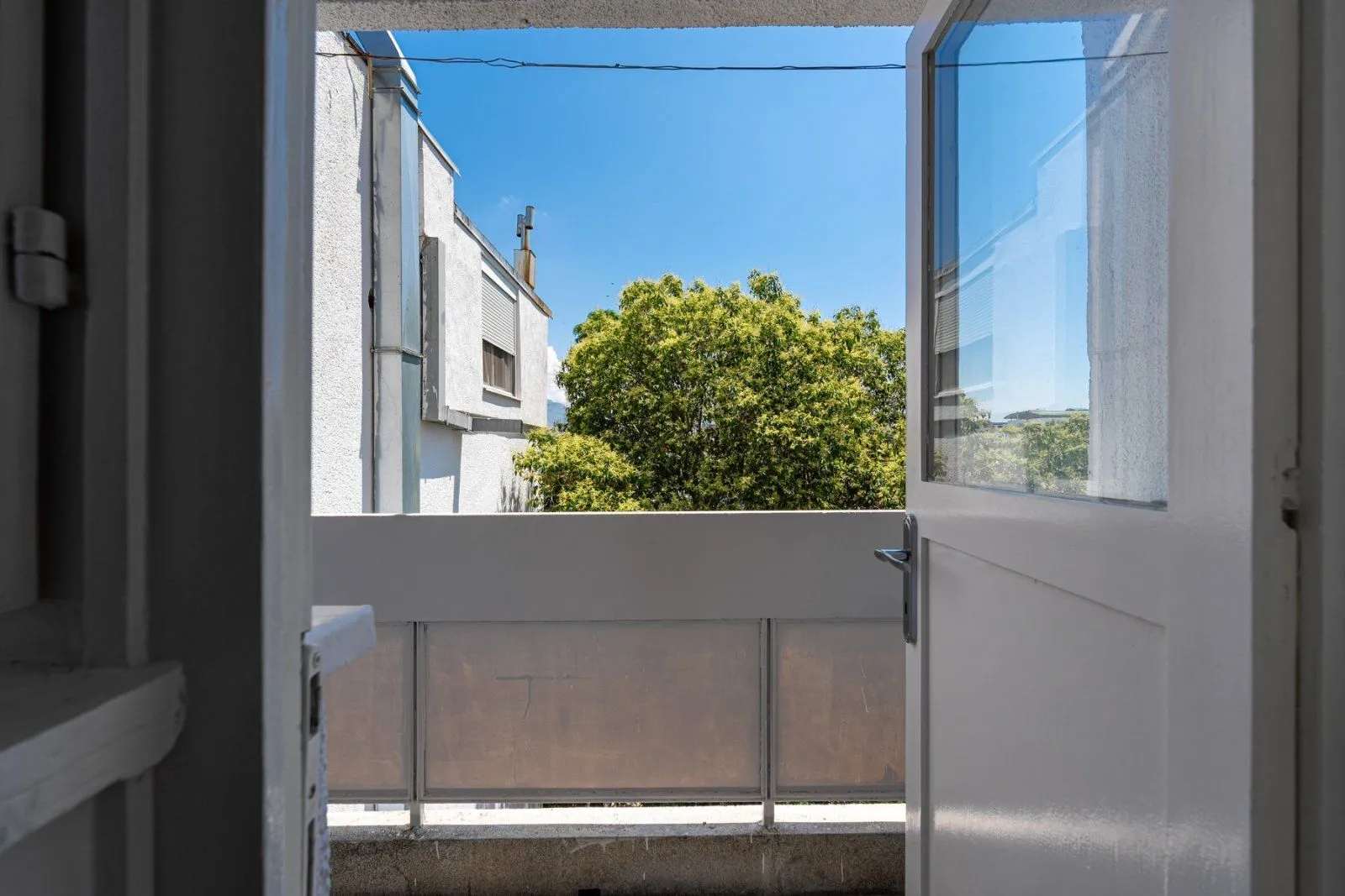 View from the balcony onto surrounding buildings and green vegetation.