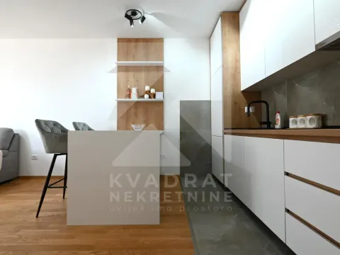 Modern kitchen with white cabinets, wooden accents, and a breakfast bar with bar stools. - image 11