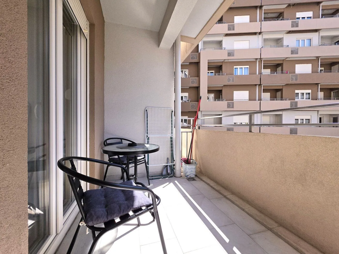 Furnished balcony with a table, chairs, and a view of surrounding buildings.