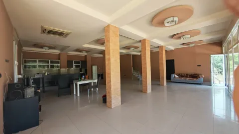 Spacious living room with pillars and a kitchen in the background. - image 9