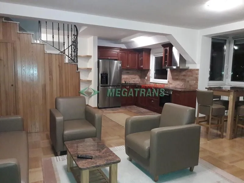 Living room with seating area, dining space, and kitchen in the background.