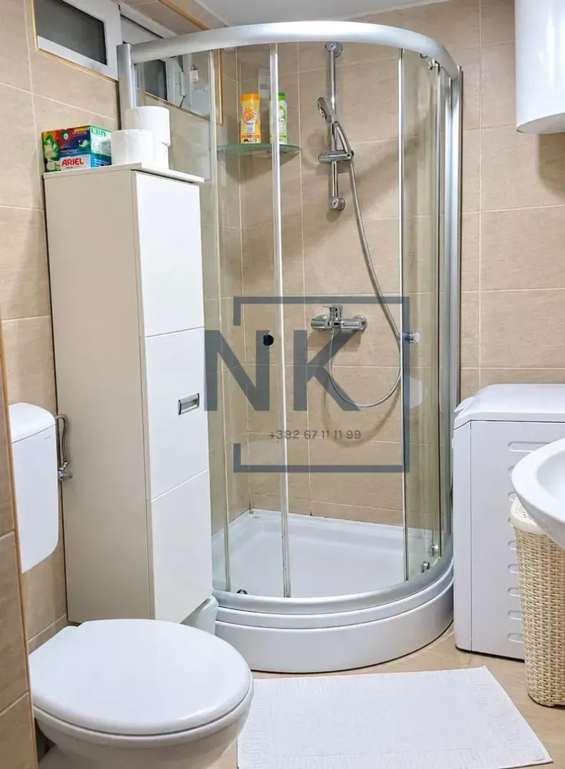 Bathroom equipped with a shower cabin, toilet, and washing machine.