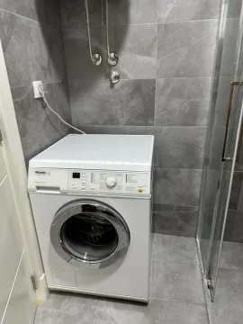 Kupatilo sa veš mašinom i sivim zidnim pločicama. - image 6