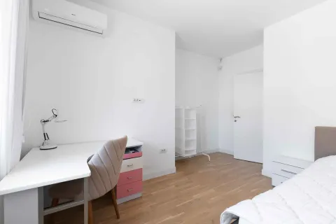 Bright and tidy bedroom with a bed, desk, and air conditioning unit. - image 28