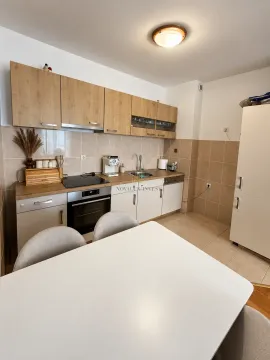 Kitchen equipped with wooden cabinetry and a dining table in the foreground. - image 4