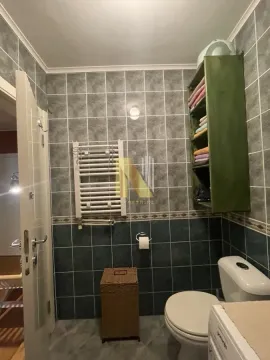 Manje kupatilo obloženo keramičkim pločicama sa toaletom i policama za peškire. - image 12