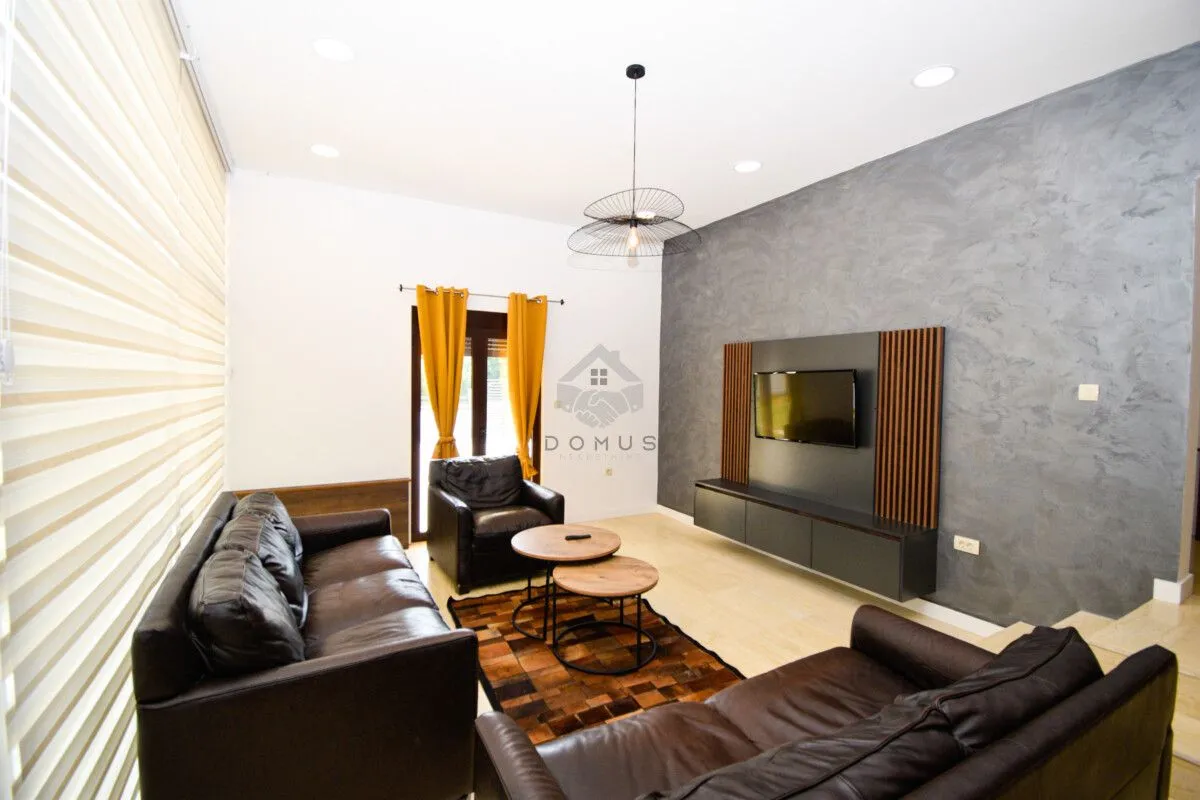 Living room with leather sofa sets, coffee table, and a TV unit on the wall with decorative finish.