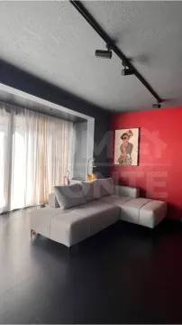 Living room with a sectional sofa, red accent wall, and dark flooring. - image 2