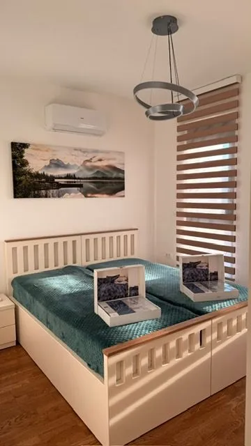 Furnished bedroom with a double bed, air conditioning, and a window with blinds.