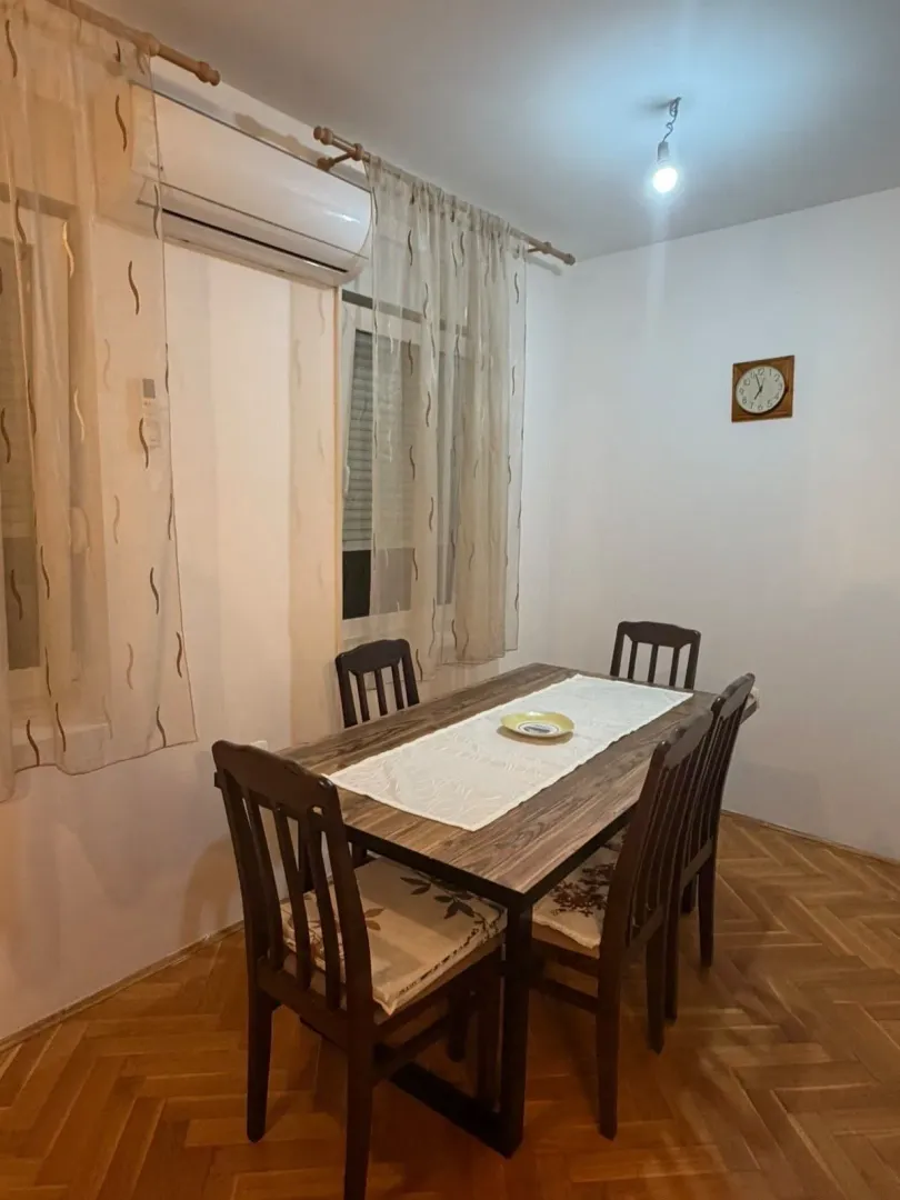 Trpezarija sa drvenim stolom i stolicama.