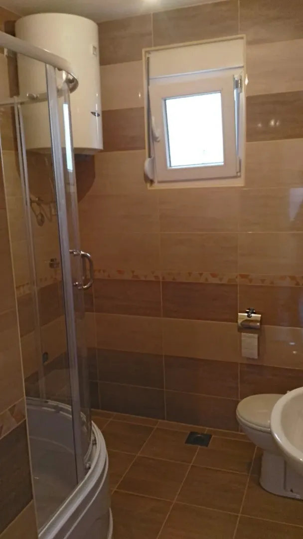 Simple bathroom with a shower cabin, toilet, and water heater.