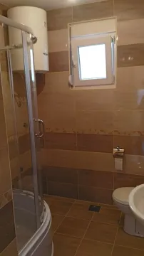 Simple bathroom with a shower cabin, toilet, and water heater. - image 14