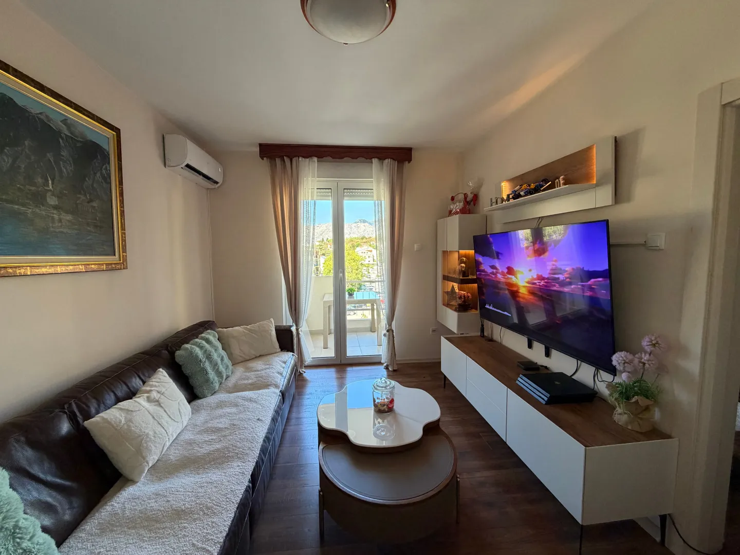 Dnevna soba sa garniturom, televizorom i izlazom na terasu.