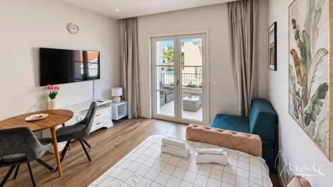Namještena spavaća soba sa krevetom, televizorom i izlazom na terasu. - image 3
