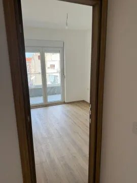 Pogled kroz vrata na praznu prostoriju sa laminatom i balkonskim vratima. - image 7