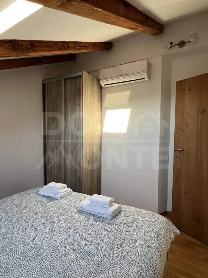 Bedroom with a bed, wardrobe, and wooden ceiling beams.